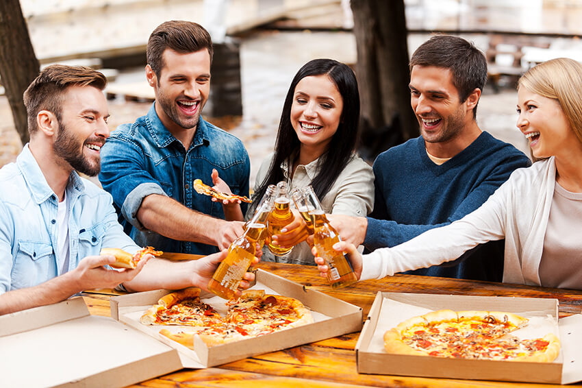 cheers-group-of-cheerful-young-people-eating-pizza-46XSSWV