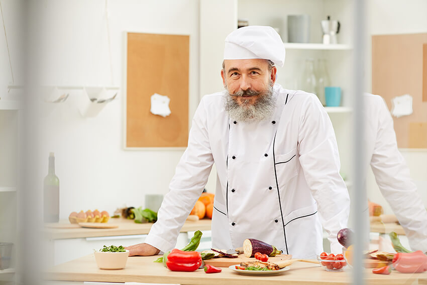 senior-chef-posing-in-kitchen-A7X9AMF